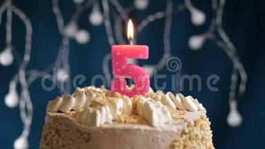 生日蛋糕，蓝色背景上有5个数字的粉红色燃烧<strong>蜡烛</strong>。 <strong>蜡烛</strong>吹灭了。 慢速运动和特写镜头