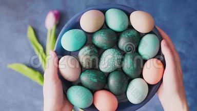 蓝色盘子上五颜六色的复活节彩蛋，蓝色背景上有郁金香。 复活节节日装饰品，复活节概念背景