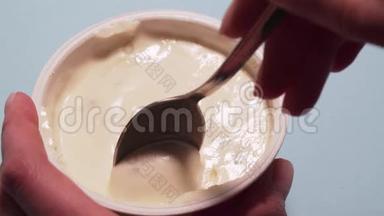 女人用勺子吃无麸质酸奶。 女人的手用勺子拿起一块干酪，放在白色的地上