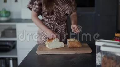 一个女人的手或一个厨师用刀子把一条面包、一条面包或一个小面包切成一块块的木切割板