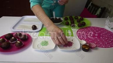 一个女人把巧克力球洒在海绵蛋糕上。 做一个土豆蛋糕。 盘子旁边有蛋糕、液体巧克力和