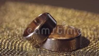 婚礼金戒指躺在闪亮的光泽表面。 光芒四射。 特写