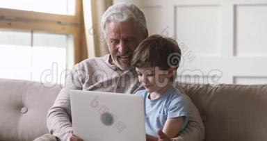 快乐的老爷爷和孙子用笔记本电脑打电话