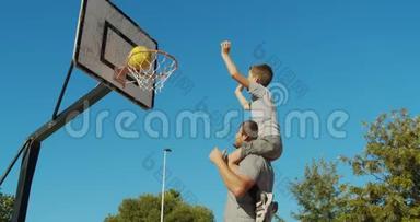 爸爸和儿子在街上<strong>打篮球</strong>，向篮子里扔一个球。