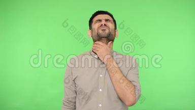 喉咙痛。 不健康的年轻人穿着衬衫<strong>摩擦</strong>脖子，痛苦地做鬼脸。 绿色背景，色度键