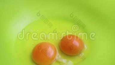 生鸡蛋落入绿色塑料碗中，慢动作特写.. 一个鸡蛋已经在那里了。 做煎饼的过程.. A.