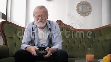 现代的有胡子和视力眼镜的祖父玩家坐在沙发上玩电子游戏，拿着操纵杆