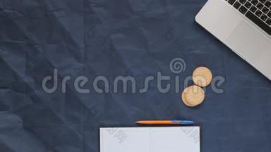 在蓝色背景、皱巴巴的纸张、复印空间上可以看到的笔记本电脑、笔记本、笔、咖啡和饼干