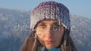 一个年轻迷人的冰冻女子在冬天的风景中微笑的慢镜头肖像。