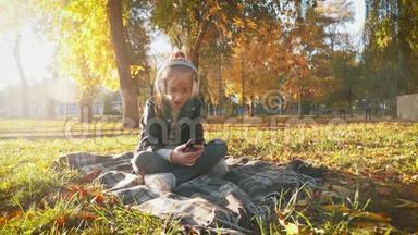 年轻女孩戴着耳机听音乐，在秋天的城市公园里唱最喜欢的歌。 女孩是个了不起的人