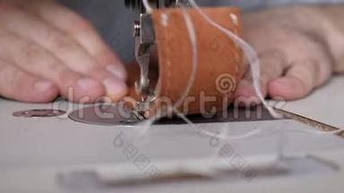 在私人皮革工艺品店工作缝纫机，缝纫带正在加工中。 工作中的裁缝。 男裁缝工