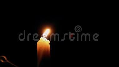 一支美丽的蜡烛在黑暗的房间里燃烧，一支温暖的黄色蜡烛在黑暗中静静地燃烧。