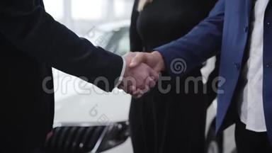 在汽车经销店里不可辨认的男人握手。 高加索交易员在展厅中与中东客户握手