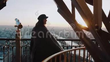 年轻美丽的微笑女子摆姿势，在埃菲尔铁塔顶部旋转，观看绚丽的日落天空全景慢动作。