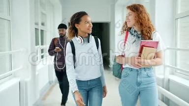 快乐的年轻女士在大学大厅里慢悠悠地走着，做着击掌