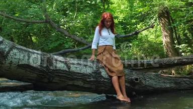 女孩坐在树干上的河水中浇水。
