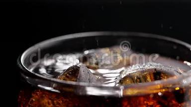 可乐饮料的特写与气泡在缓慢的运动。 带冰的可乐和玻璃中的气泡