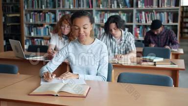 非裔美国女孩在图书馆读书，从男学生那里拿书