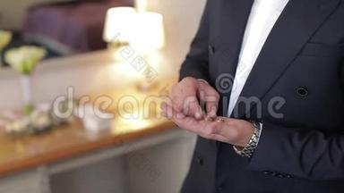英俊的新郎手里拿着结婚戒指。 结婚的早晨。 商人