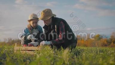 年轻的母亲和她的女儿在农场收割蔬菜。 收割期间农民家庭小组剪影