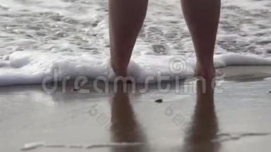 赤足的女人站在海边的沙滩上，一阵一阵地涌进她的脚。 自我反省，孤独