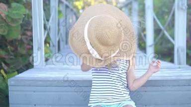 小女孩生气了，把一顶大帽子扔在沙子上。