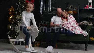 新年-一家人坐在沙发上的毯子下，旁边的女儿骑着一匹玩具马