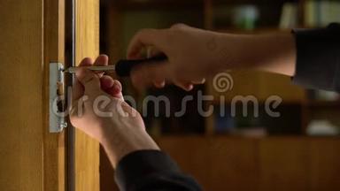 木匠修理门锁。 安装门把手.. 汉德曼拧紧门铰链。 修理工的手和一个