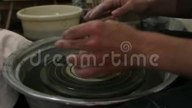 主人创造一个白色粘土产品。 主人`用陶工的轮子特写雕刻一件粘土制品。