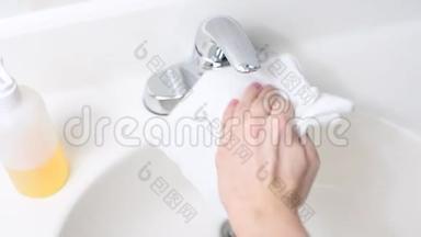女人正在用洗涤剂清洗浴室的水槽和水龙头