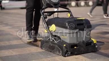 看门人使用手动电动推式清扫车，用湿热压垫圈清扫城市人行道铺板