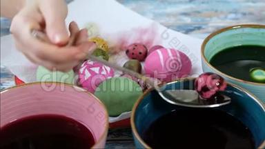 用彩蛋颜料给复活节彩蛋染色的女人手特写。五颜六色的复活节彩蛋。复活节的准备
