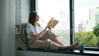 漂亮的女孩在家坐在窗台上<strong>翻书</strong>