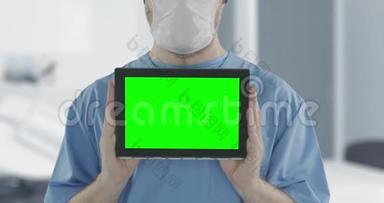 医生戴着医用口罩，用绿色屏幕拍摄平板电脑。 阿尔法哑光，便于图片或视频