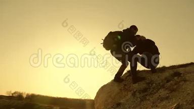 在日落的背景下，游客们爬上<strong>山崖</strong>的剪影，互相帮助`手。 提供帮助
