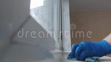 一个戴着蓝色橡胶手套的妇女在窗台上搓抹布，<strong>打扫房间</strong>