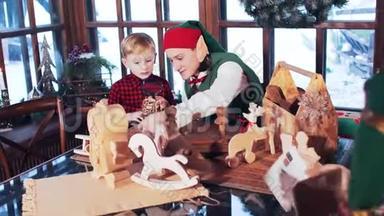 一个穿红色衬衫的男孩和一个圣诞精灵玩木玩具