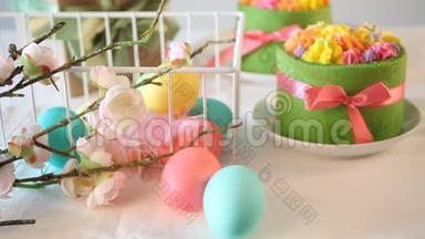 春季复活节节日餐桌。 背景上有黄油奶油花和五颜六色的鸡蛋的小绿色蛋糕。 五彩缤纷