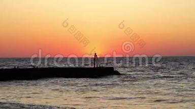 日出时孤独的人。 海滩上的一个人迎接黎明。 海波