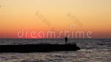日出时孤独的人。 海滩上的一个人迎接黎明。 海<strong>波浪波浪波浪波浪波浪波浪</strong>浪