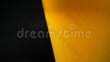 在深色背景下的玻璃杯中加入亮黄色啤酒