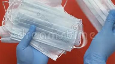 护理人员在红色背景下，用蓝色医用手套保护手中的抗病毒口罩持有设备