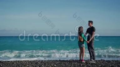 青年男女来到蔚蓝海岸，拥抱.. 海浪突然急促起来，弄湿了他们的脚。 情人