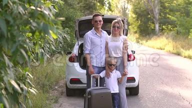 幸福的家庭靠近汽车后备箱，手提箱在一条空路在树林里。