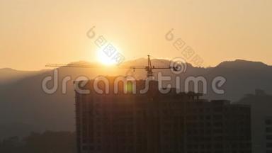 建筑工地上的一架<strong>塔式</strong>起重机和城市里的一座摩天大楼上空日出。 时光流逝。