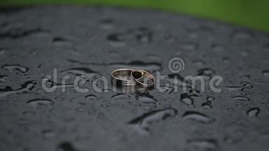 美丽的金色结婚戒指在潮湿的表面与水滴。