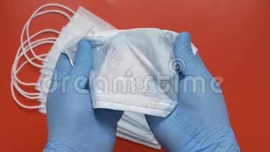 护理人员在红色背景下，用蓝色医用手套保护手中的抗病毒口罩持有设备
