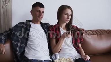 一对情侣在新房的沙发上看<strong>电视</strong>，用<strong>电视遥控器</strong>一起看电影