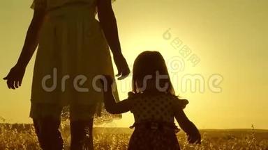 小女儿和妈妈牵着手在田野里走来走去。 宝贝牵着妈妈`手。 幸福的一家人晚上出去散步
