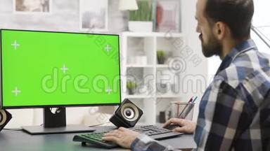 用绿色屏幕放大在电脑上工作的年轻人的<strong>视差</strong>镜头